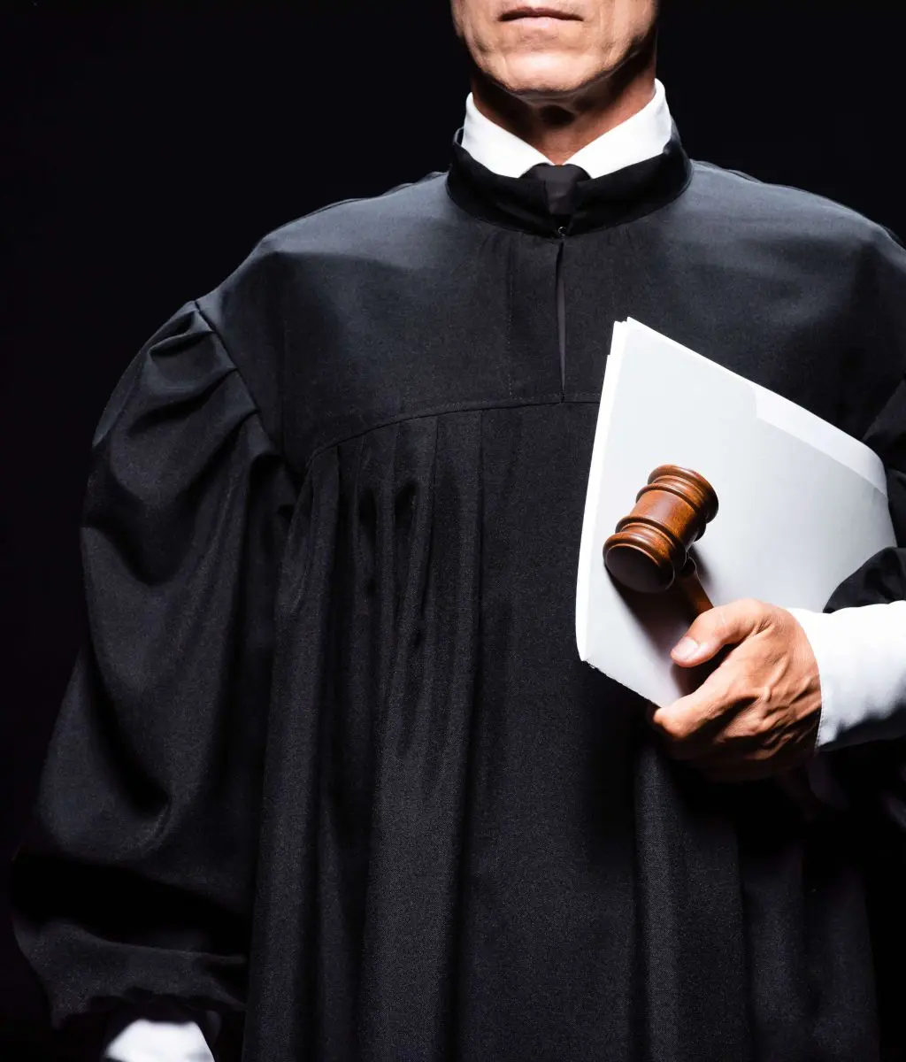cropped view of judge in judicial robe holding gavel and papers isolated on black