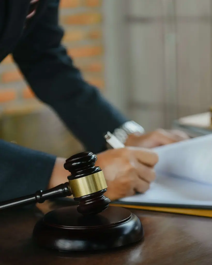Justice and law concept. Male judge in a courtroom the gavel, working on wood table in sun light.