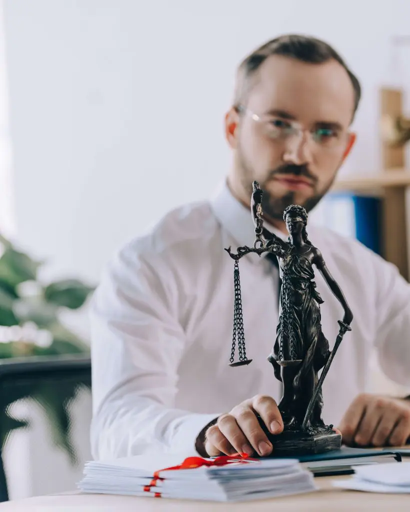 selective focus of lawyer in eyeglasses with femida at workplace in office