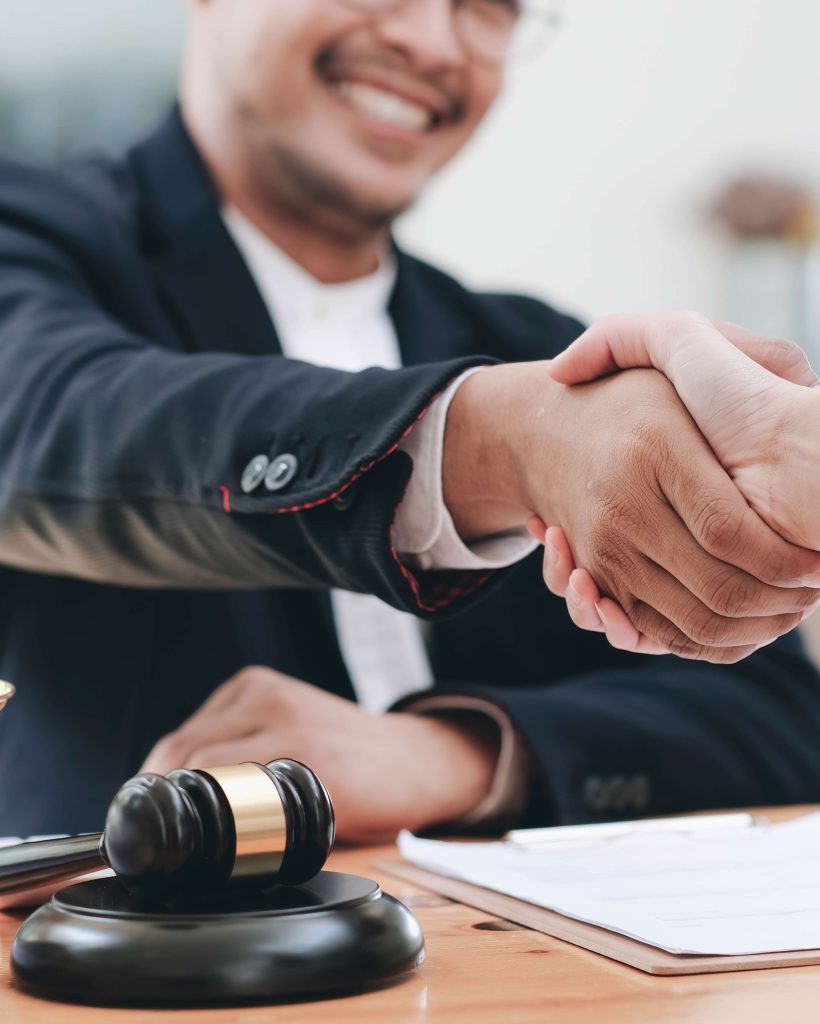 Businessman shaking hands to seal a deal with his partner lawyers or attorneys discussing